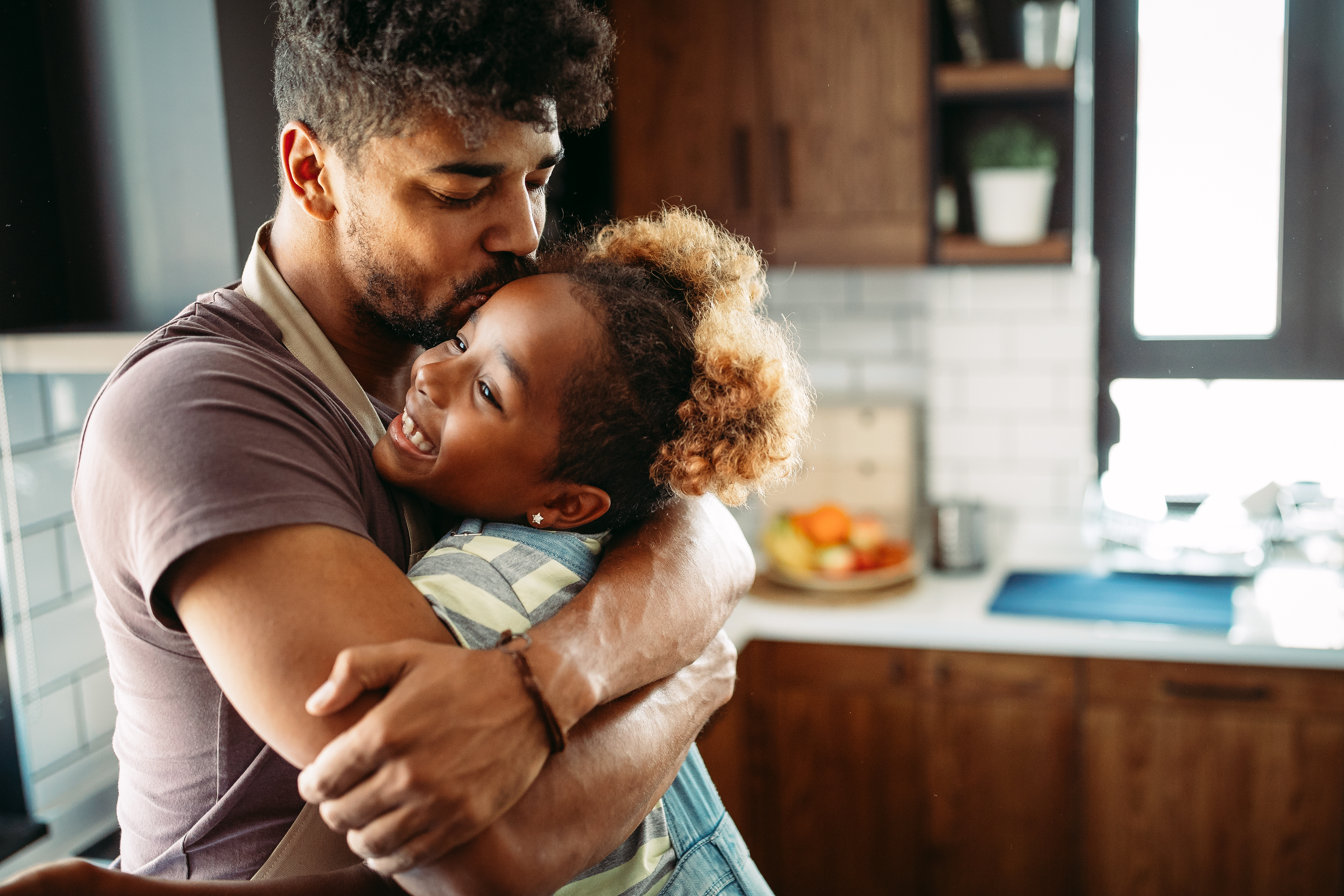 Dad giving daughter a hug while standing in the kitchen