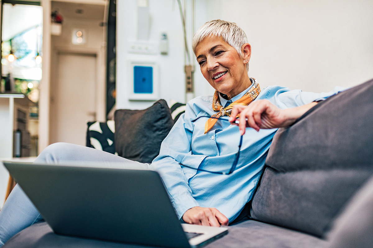 Woman looking at something on her laptop while sitting on a couch